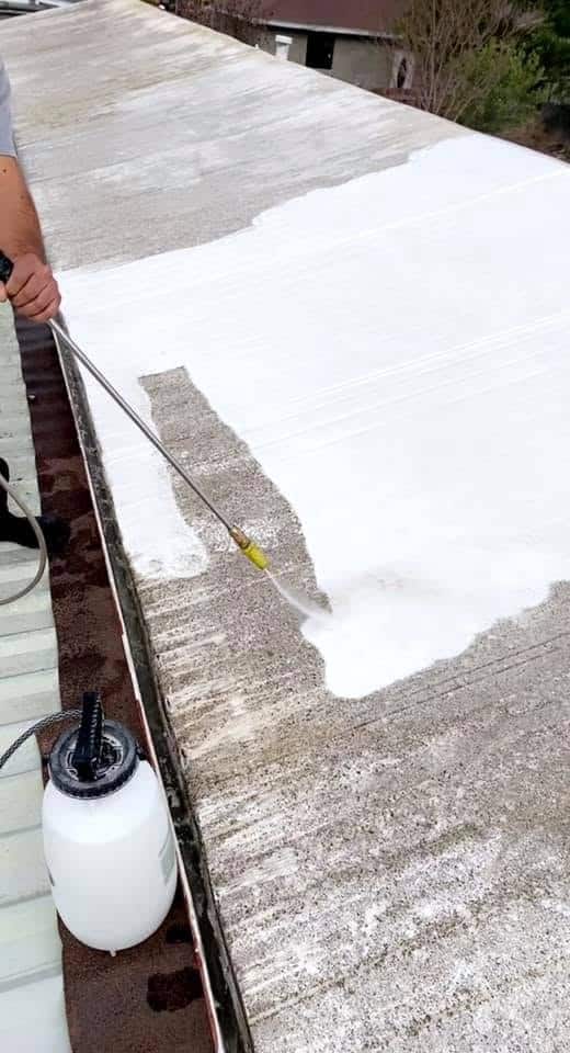 Powerwashing Applying white shotcrete on a concrete surface for waterproofing or repair.