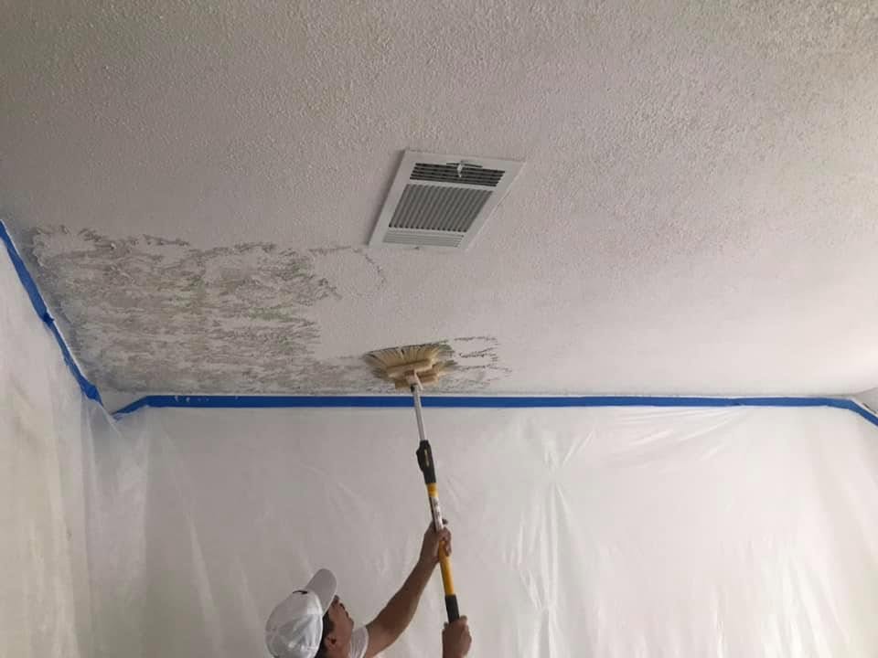 Specialty Painting A worker applying spray gunite or shotcrete to ceiling surface in construction site.