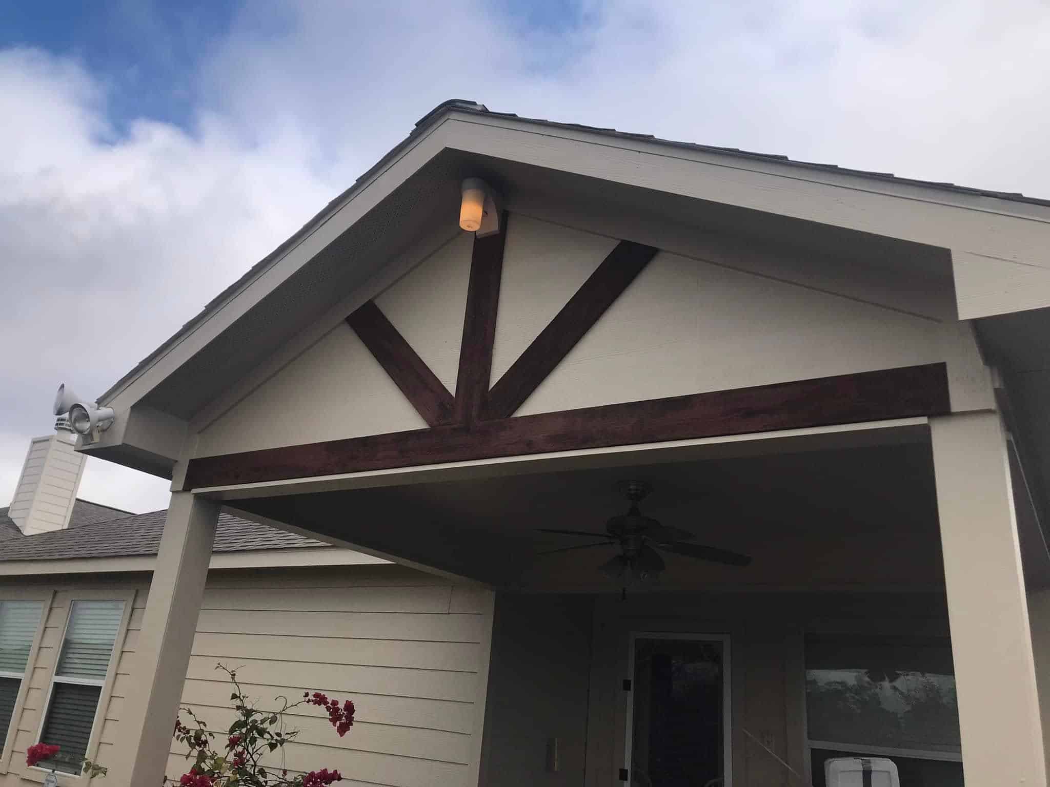 Exterior Trim Covered porch with ceiling fan and decorative wood beams in a residential home.