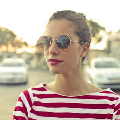 Home 2 Woman wearing sunglasses and a red and white striped shirt outdoors.